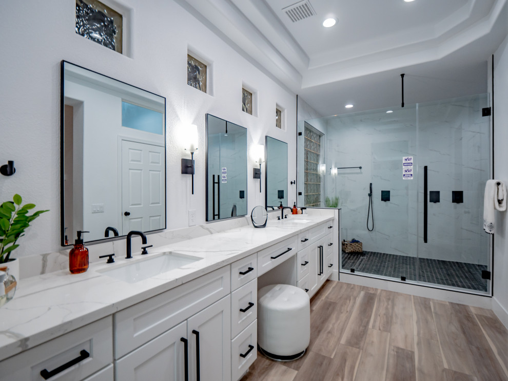Large contemporary master bathroom in Las Vegas with white cabinets, a double shower, white walls, an undermount sink, brown floor, a hinged shower door, white benchtops, a shower seat, a double vanity, a built-in vanity, recessed, shaker cabinets, a one-piece toilet, vinyl floors and quartzite benchtops.