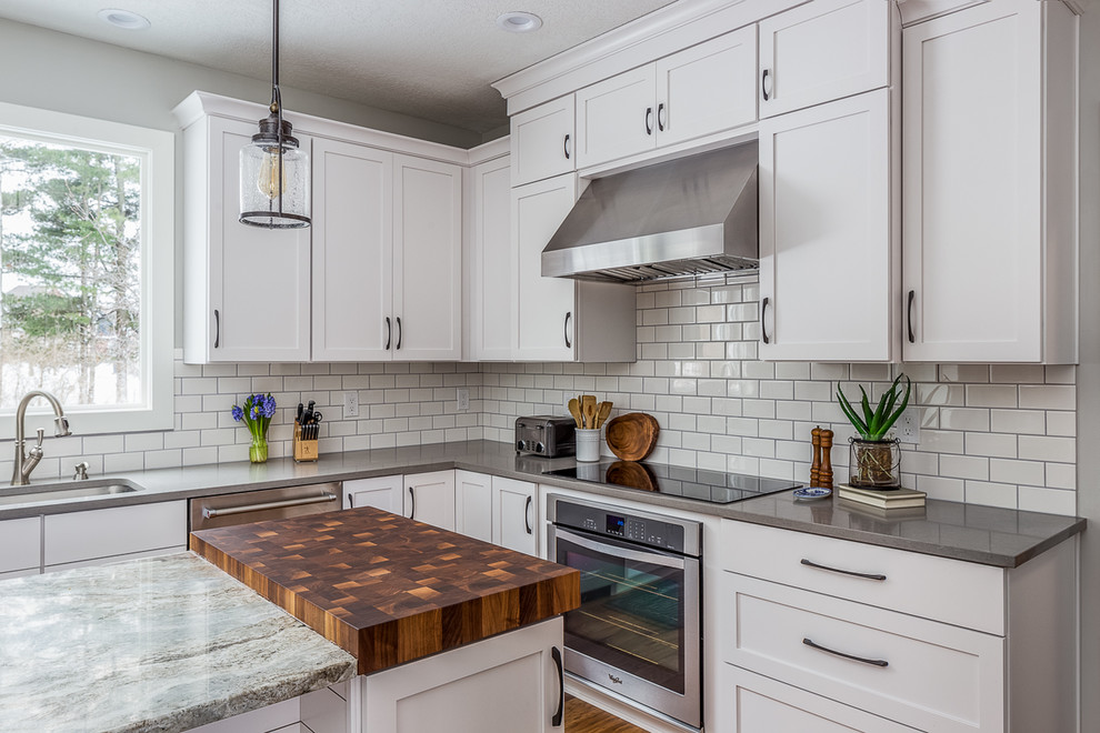 Eat-in kitchen - large transitional l-shaped eat-in kitchen idea with a drop-in sink, recessed-panel cabinets, white cabinets, quartzite countertops, white backsplash, stainless steel appliances and an island