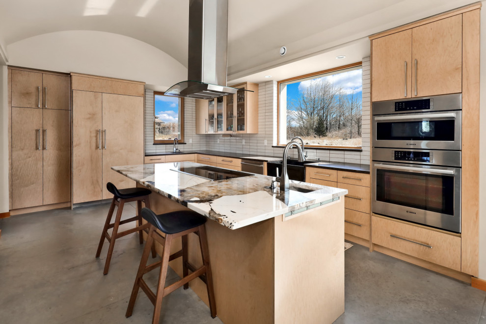 Large mountain style l-shaped concrete floor and gray floor eat-in kitchen photo in Seattle with a farmhouse sink, flat-panel cabinets, light wood cabinets, quartz countertops, gray backsplash, ceramic backsplash, stainless steel appliances, an island and multicolored countertops