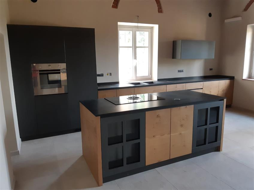 Large industrial open plan kitchen in Turin with concrete benchtops, with island and black benchtop.
