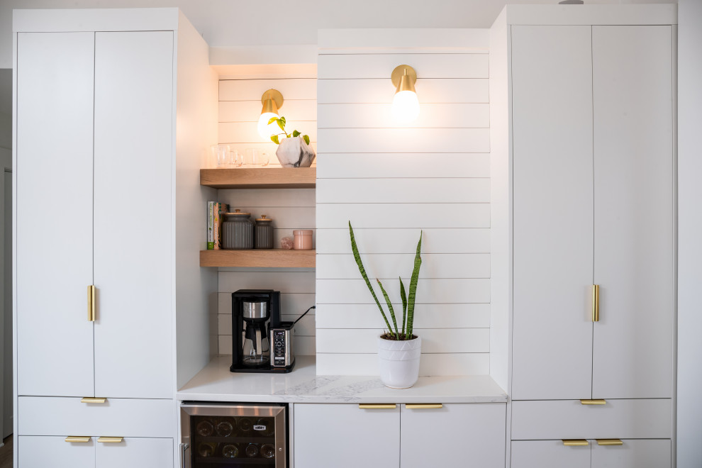 Mid-sized minimalist l-shaped light wood floor, brown floor and vaulted ceiling eat-in kitchen photo in Other with an undermount sink, flat-panel cabinets, white cabinets, quartzite countertops, white backsplash, quartz backsplash, stainless steel appliances, an island and white countertops