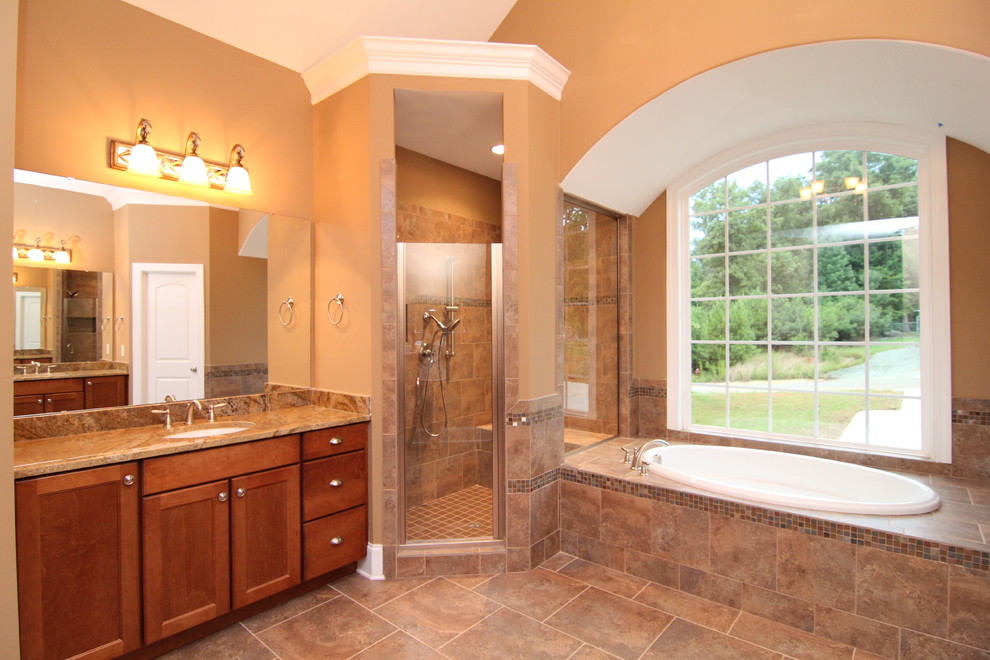 Inspiration for a large traditional master bathroom in Raleigh with an undermount sink, recessed-panel cabinets, medium wood cabinets, granite benchtops, an alcove tub, a corner shower, a one-piece toilet, brown tile, ceramic tile, beige walls and ceramic floors.