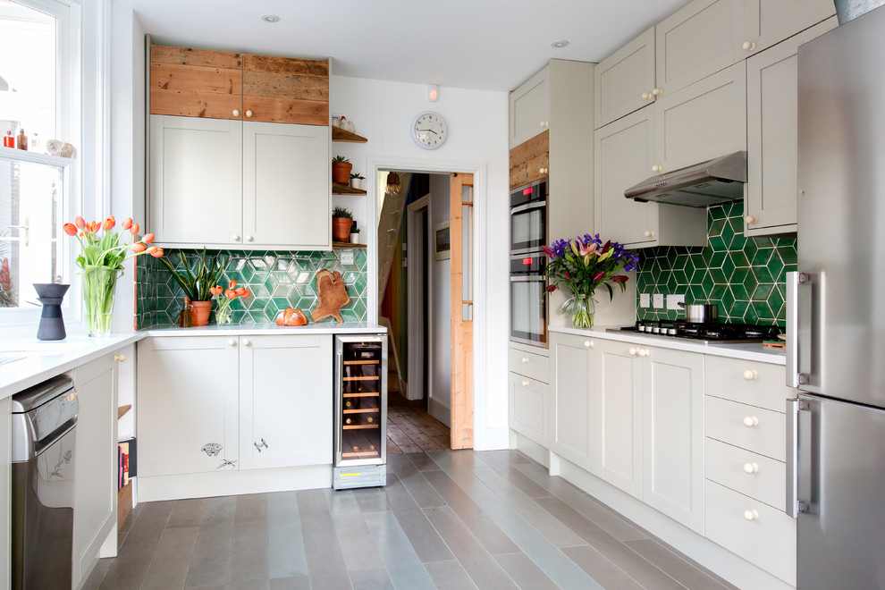 Inspiration for a mid-sized transitional single-wall open plan kitchen in London with green splashback, ceramic splashback, porcelain floors, an undermount sink, shaker cabinets, beige cabinets and stainless steel appliances.