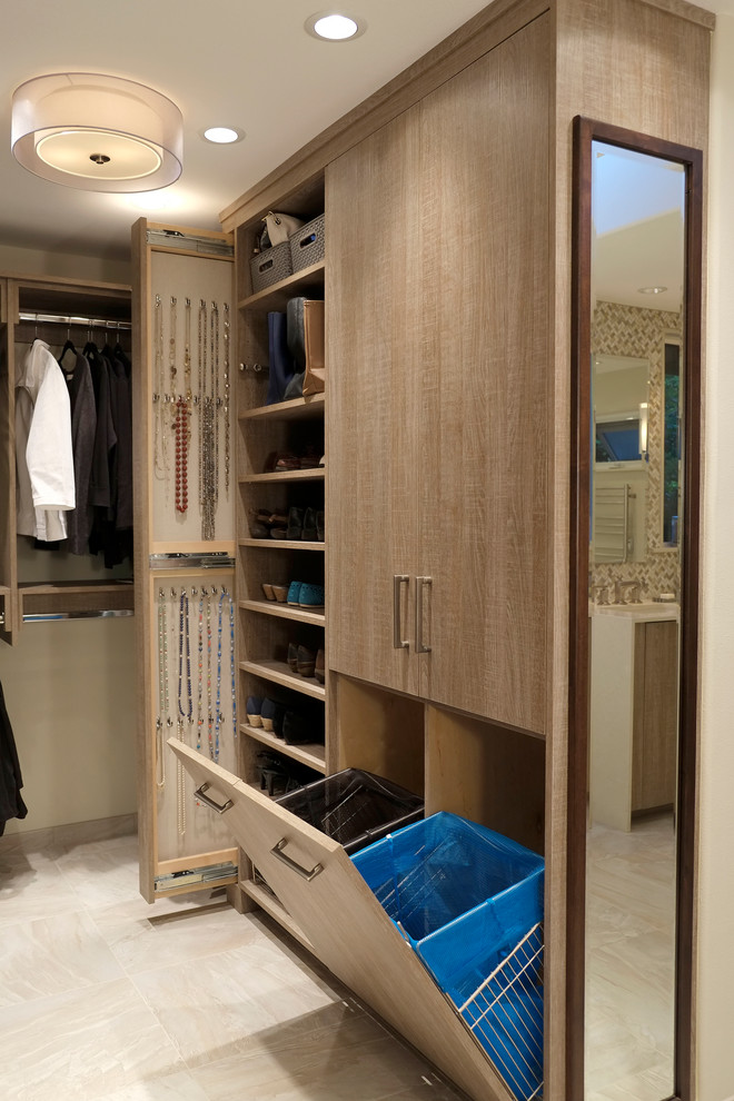 This is an example of a large contemporary walk-in wardrobe in Seattle with flat-panel cabinets, light wood cabinets and porcelain floors.
