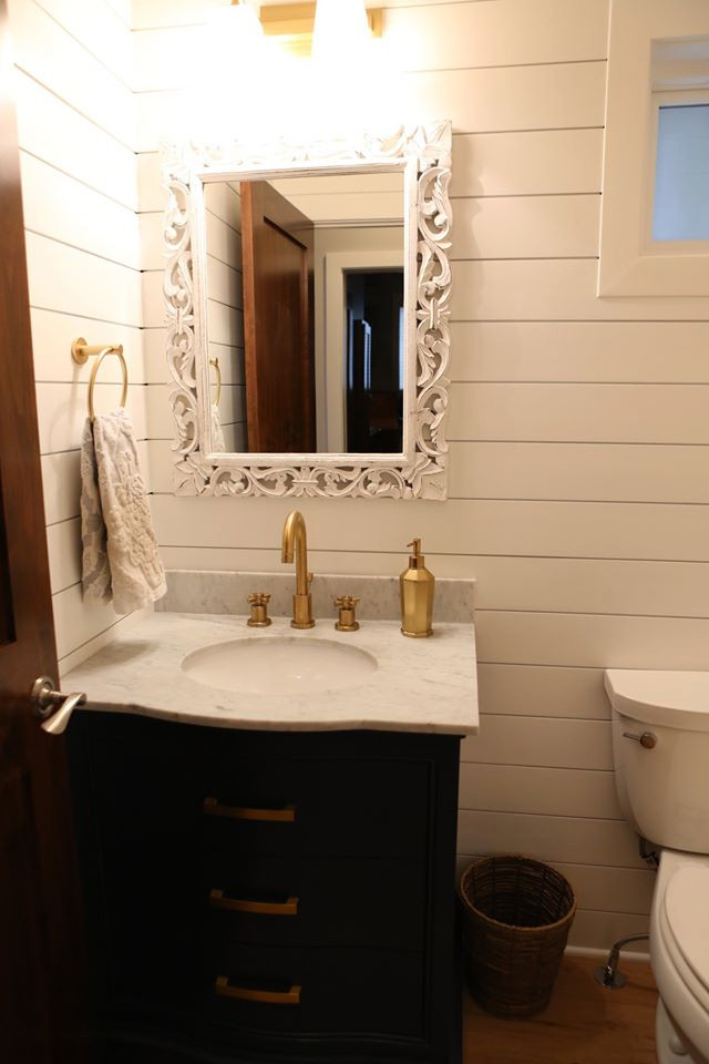 ミネアポリスにある高級な小さなトラディショナルスタイルのおしゃれな浴室 (落し込みパネル扉のキャビネット、青いキャビネット、一体型トイレ	、白い壁、淡色無垢フローリング、アンダーカウンター洗面器、クオーツストーンの洗面台、茶色い床、白い洗面カウンター、トイレ室、洗面台1つ、独立型洗面台、塗装板張りの壁) の写真