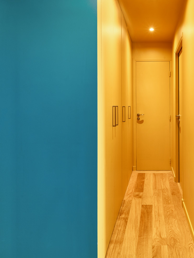 Inspiration for a mid-sized contemporary medium tone wood floor and brown floor hallway remodel in Paris with yellow walls