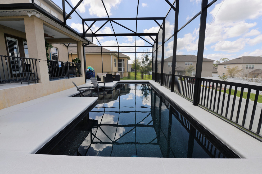 Modelo de piscina tradicional de tamaño medio rectangular en patio trasero con losas de hormigón