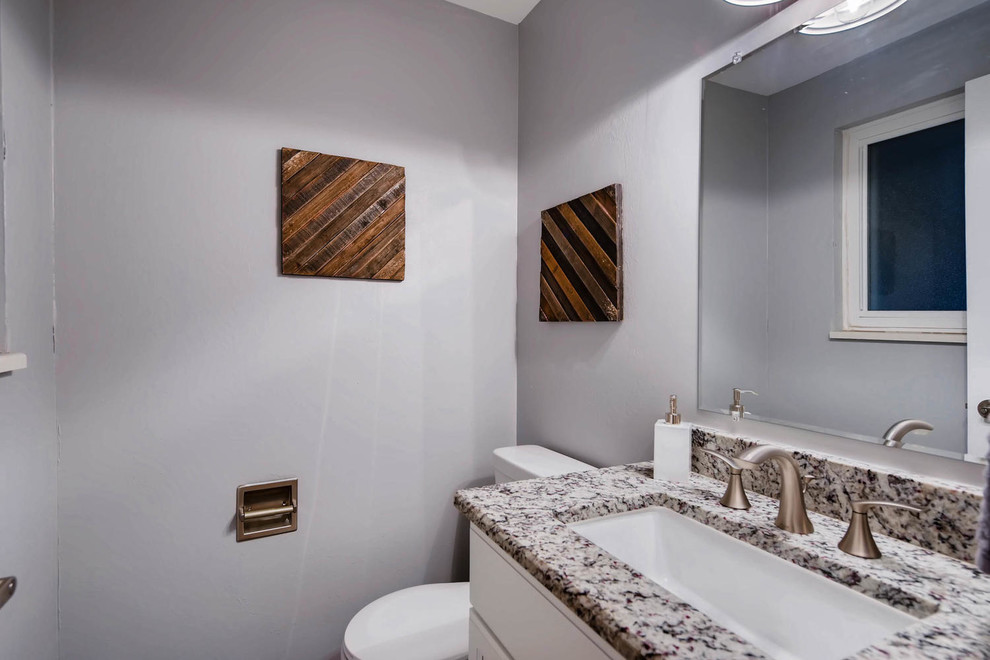 Photo of a small transitional 3/4 bathroom in Denver with recessed-panel cabinets, white cabinets, a two-piece toilet, grey walls, medium hardwood floors, an undermount sink, granite benchtops and brown floor.
