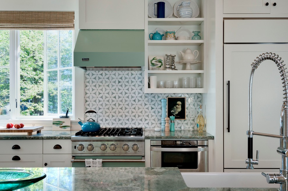 This is an example of a beach style kitchen in Portland Maine with a farmhouse sink, open cabinets, white cabinets, grey splashback and panelled appliances.