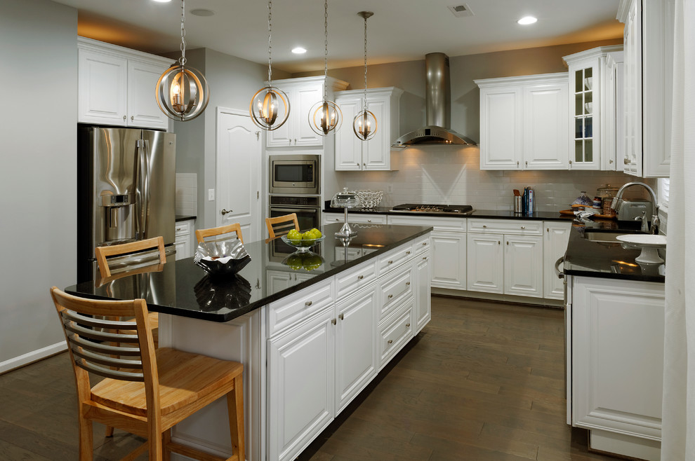 Inspiration for a traditional u-shaped kitchen in DC Metro with an undermount sink, raised-panel cabinets, white cabinets, white splashback, subway tile splashback and stainless steel appliances.