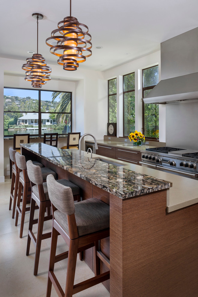 This is an example of a mid-sized contemporary galley eat-in kitchen in San Francisco with an undermount sink, glass-front cabinets, dark wood cabinets, green splashback, with island, quartz benchtops, stainless steel appliances and limestone floors.