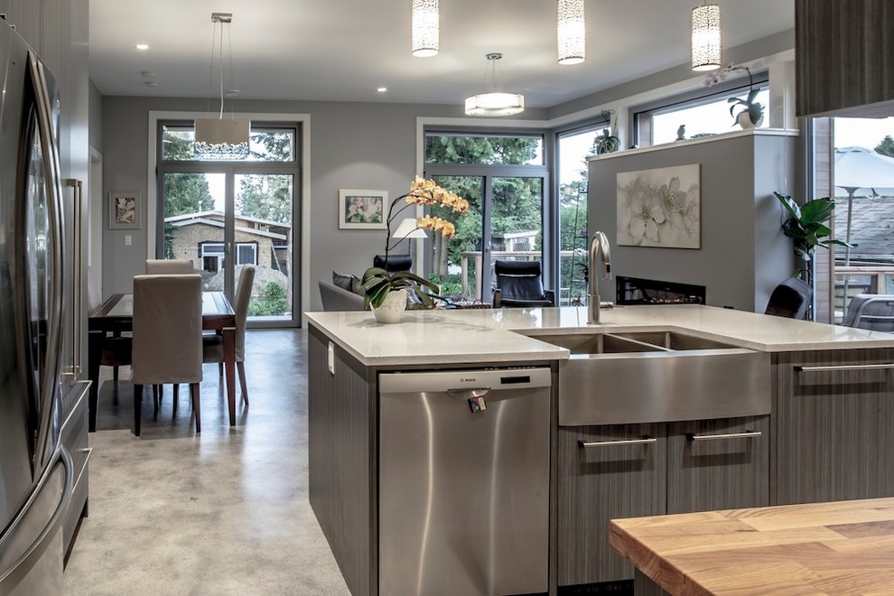 Design ideas for a mid-sized contemporary single-wall eat-in kitchen in Vancouver with with island, flat-panel cabinets, brown cabinets, wood benchtops, white splashback, ceramic splashback, stainless steel appliances, a drop-in sink and concrete floors.