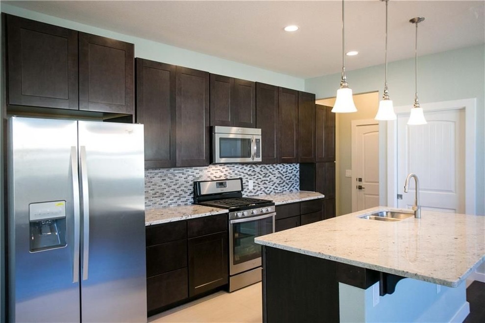 Inspiration for a mid-sized transitional single-wall porcelain tile and beige floor eat-in kitchen remodel in Austin with a double-bowl sink, shaker cabinets, dark wood cabinets, granite countertops, gray backsplash, mosaic tile backsplash, stainless steel appliances, an island and gray countertops