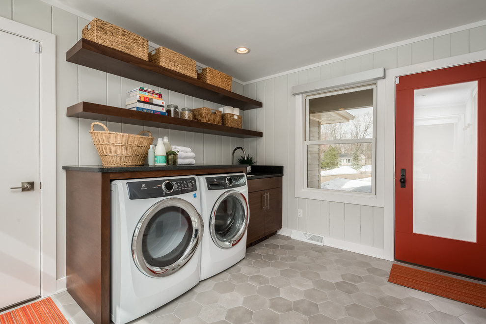 Design ideas for a mid-sized midcentury single-wall laundry room in New York with an undermount sink, dark wood cabinets, granite benchtops, grey walls, ceramic floors, a side-by-side washer and dryer, grey floor, black benchtop and open cabinets.