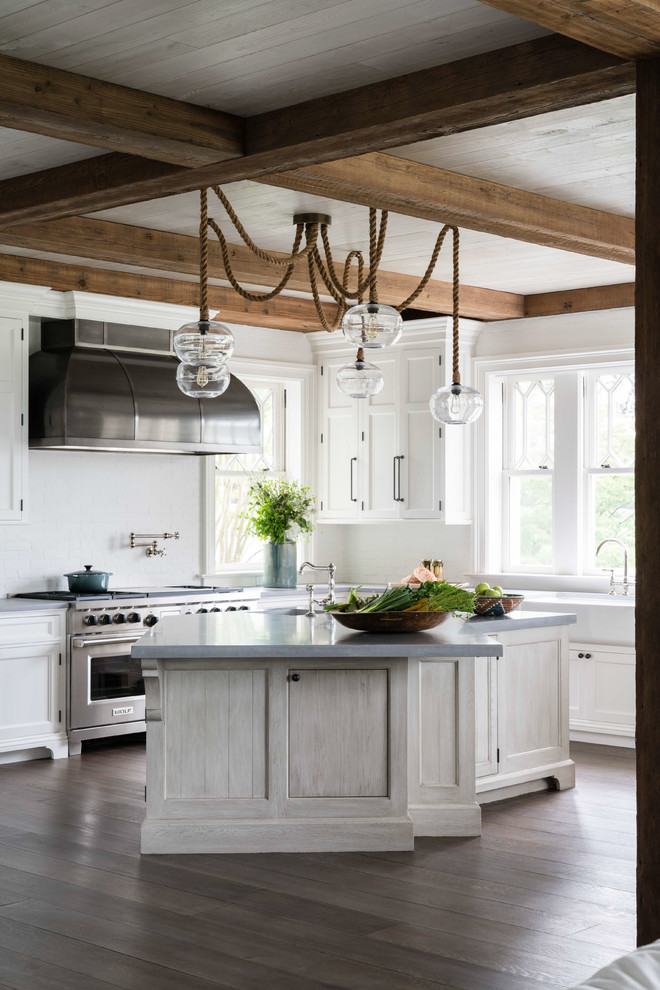 Design ideas for a large beach style eat-in kitchen in Other with a farmhouse sink, recessed-panel cabinets, white cabinets, concrete benchtops, white splashback, brick splashback, stainless steel appliances, light hardwood floors, with island, grey floor and grey benchtop.