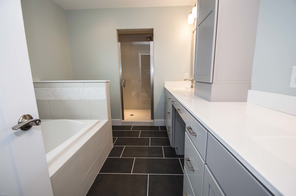 Mid-sized transitional 3/4 gray tile and porcelain tile porcelain tile and black floor drop-in bathtub photo in Chicago with shaker cabinets, gray cabinets, gray walls, an undermount sink, solid surface countertops and a hinged shower door