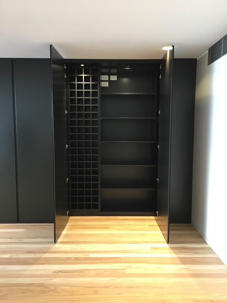 Design ideas for a small modern wine cellar in Sydney with medium hardwood floors, display racks and brown floor.