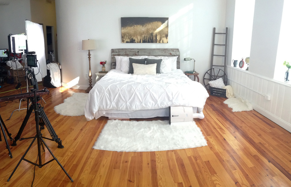 Photo of a mid-sized traditional loft-style bedroom in Providence with white walls, medium hardwood floors and no fireplace.