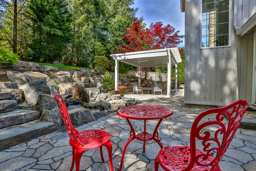 Mid-sized transitional backyard patio in Seattle with a fire feature, natural stone pavers and a pergola.