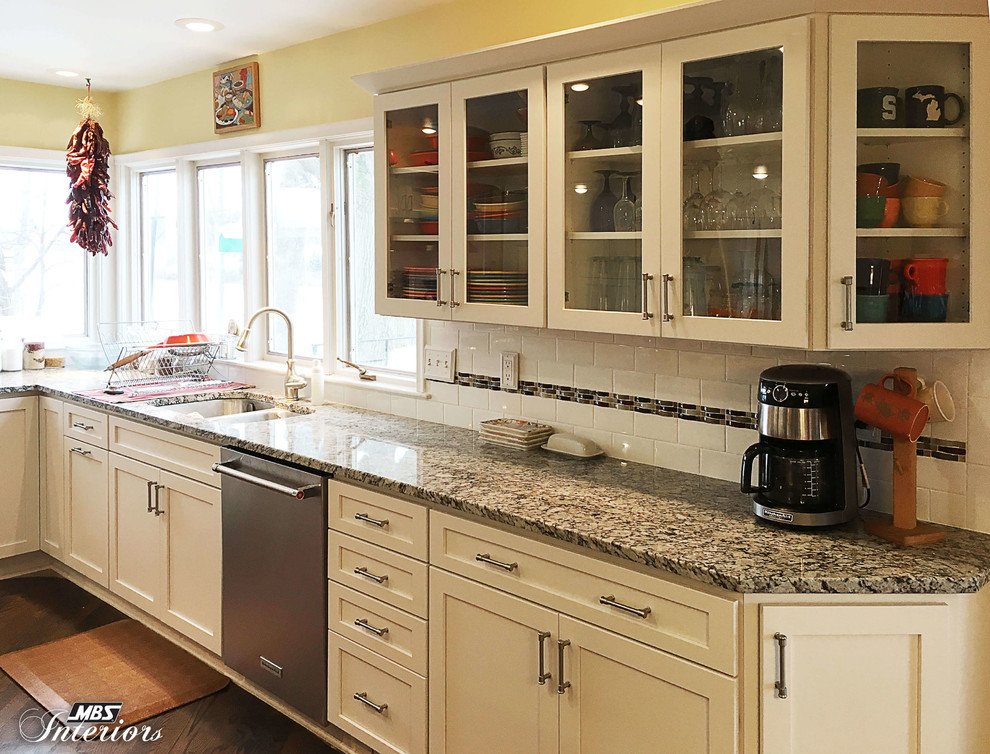 Example of a huge transitional u-shaped medium tone wood floor and brown floor eat-in kitchen design with an undermount sink, shaker cabinets, white cabinets, granite countertops, white backsplash, subway tile backsplash, stainless steel appliances and an island