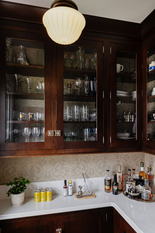 Inspiration for a victorian l-shaped medium tone wood floor and brown floor wet bar remodel in Boston with an undermount sink, glass-front cabinets, dark wood cabinets, quartz countertops, white backsplash, quartz backsplash and white countertops