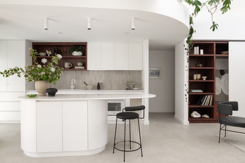 Design ideas for a contemporary l-shaped open plan kitchen in Perth with an undermount sink, flat-panel cabinets, white cabinets, grey splashback, white appliances, with island, grey floor and white benchtop.