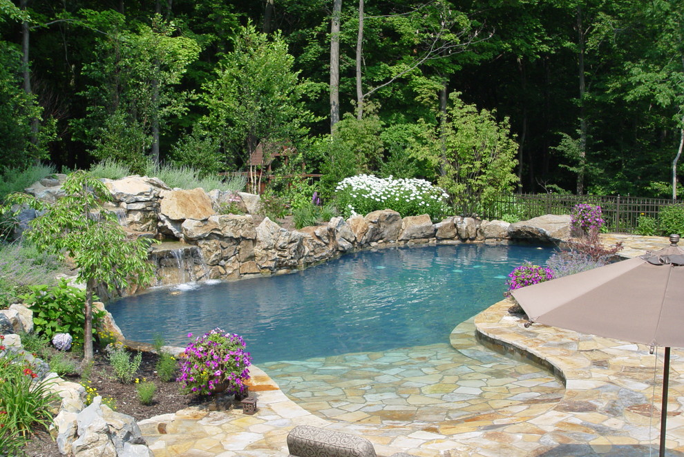 Large traditional backyard custom-shaped natural pool in New York with a water feature and natural stone pavers.