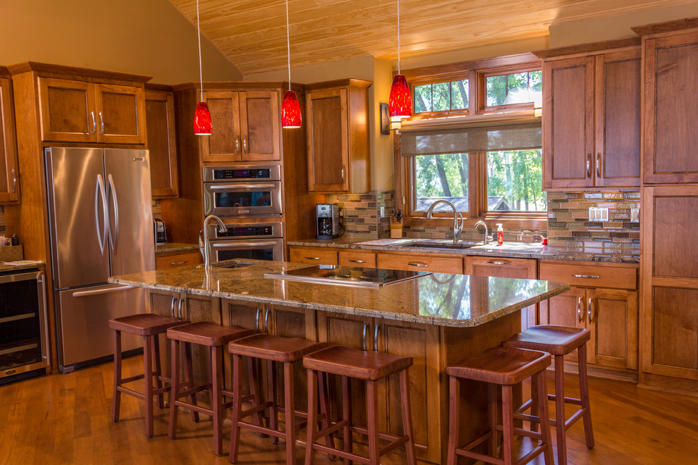 Mid-sized transitional l-shaped medium tone wood floor open concept kitchen photo with an undermount sink, recessed-panel cabinets, medium tone wood cabinets, granite countertops, multicolored backsplash, glass tile backsplash, stainless steel appliances and an island