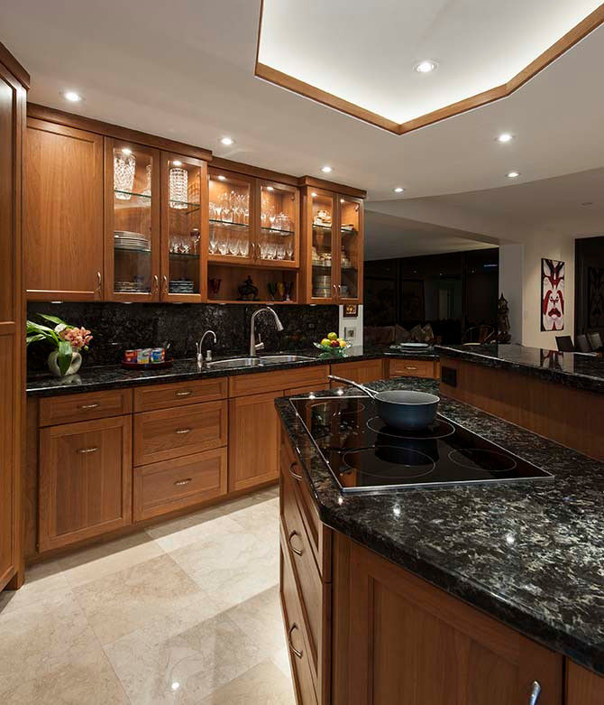 Photo of a large traditional u-shaped eat-in kitchen in Hawaii with an undermount sink, recessed-panel cabinets, dark wood cabinets, granite benchtops, multi-coloured splashback, granite splashback, panelled appliances, travertine floors, with island, beige floor, multi-coloured benchtop and coffered.