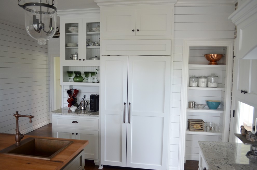 Photo of a mid-sized country u-shaped separate kitchen in Nashville with a farmhouse sink, shaker cabinets, white cabinets, granite benchtops, beige splashback, brick splashback, panelled appliances, medium hardwood floors, with island and brown floor.