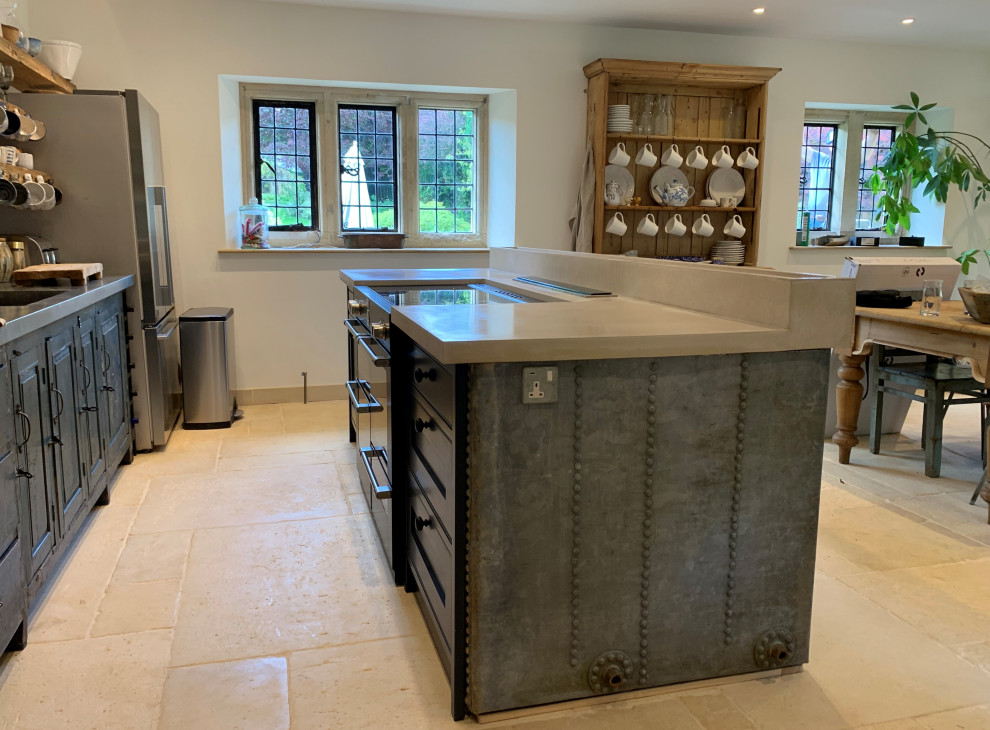 Large contemporary eat-in kitchen in Gloucestershire with distressed cabinets, concrete benchtops, grey splashback, black appliances, with island, beige floor and grey benchtop.