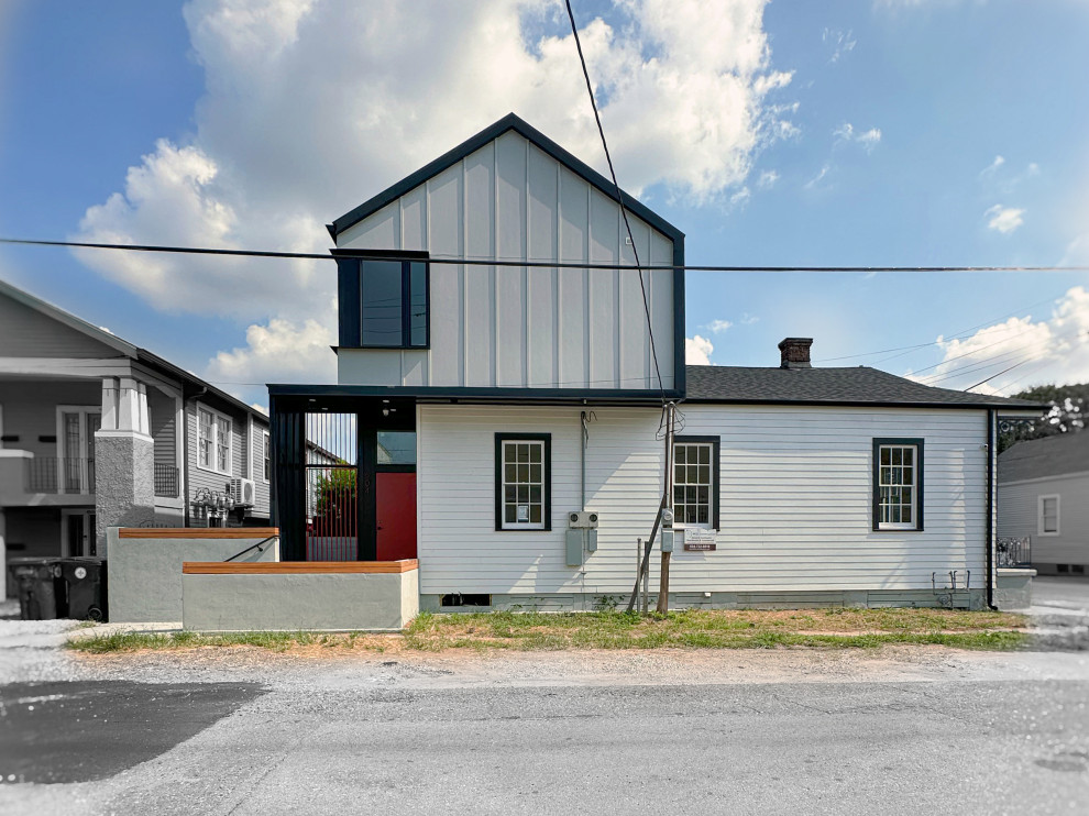 This is an example of a mid-sized modern two-storey duplex exterior in New Orleans with mixed siding, a gable roof, a metal roof, a black roof and board and batten siding.