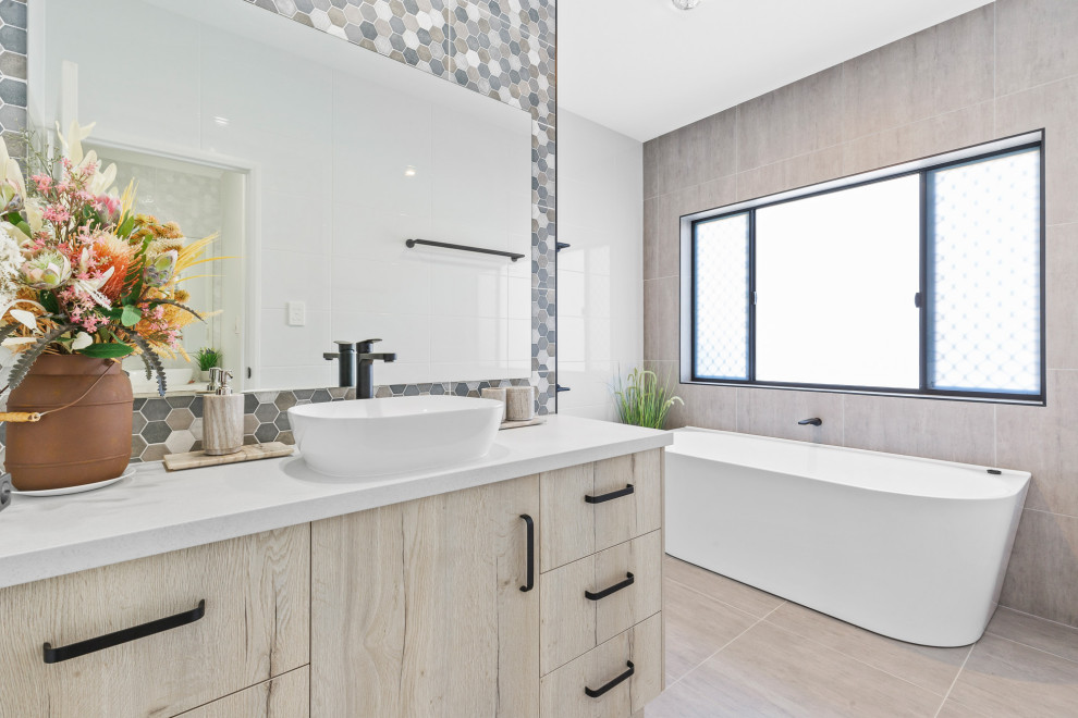This is an example of a contemporary bathroom in Other with light wood cabinets, a freestanding bath, a walk-in shower, white tiles, ceramic tiles, cement flooring, granite worktops, white worktops, a single sink and a built in vanity unit.
