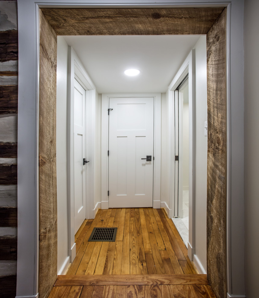 Idée de décoration pour un couloir champêtre en bois de taille moyenne avec un mur blanc, un sol en bois brun et un sol marron.