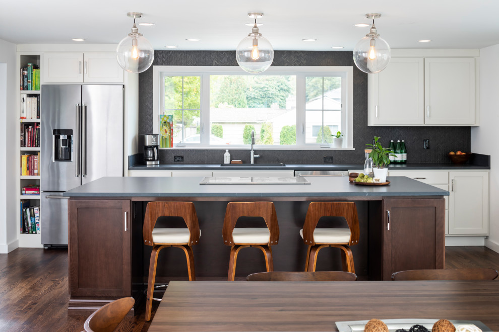 Inspiration for a transitional galley eat-in kitchen in Seattle with an undermount sink, white cabinets, soapstone benchtops, black splashback, mosaic tile splashback, stainless steel appliances, with island, black benchtop, shaker cabinets, dark hardwood floors and brown floor.
