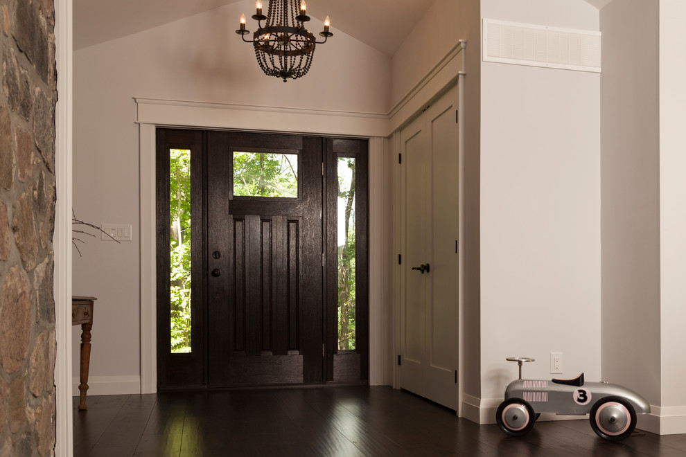 This is an example of a transitional entryway in Toronto with white walls, dark hardwood floors, a single front door and a black front door.