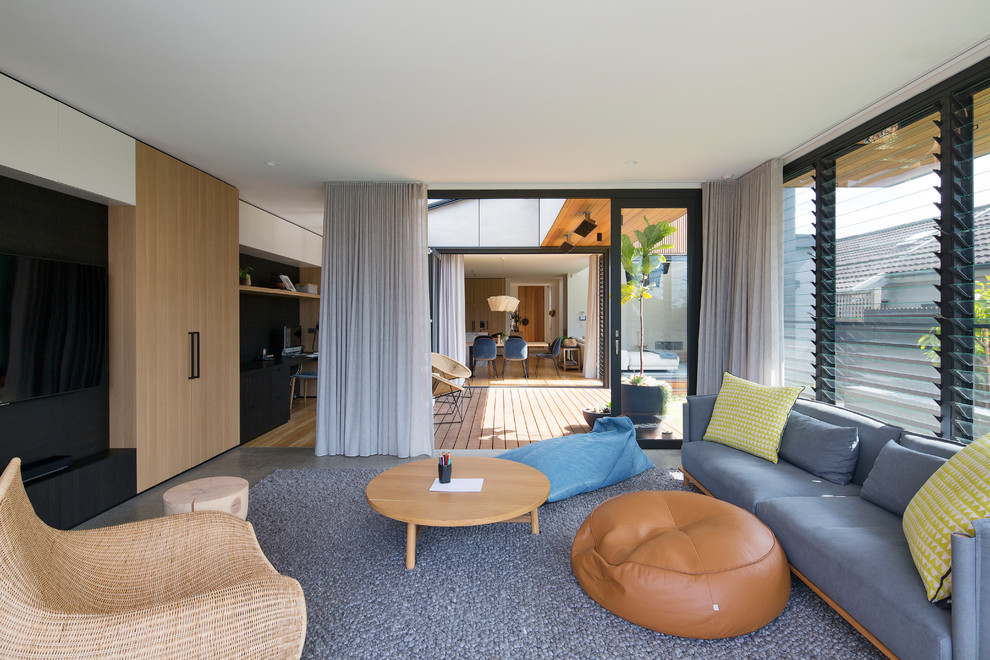 This is an example of a mid-sized contemporary open concept family room in Sydney with a wall-mounted tv and grey floor.