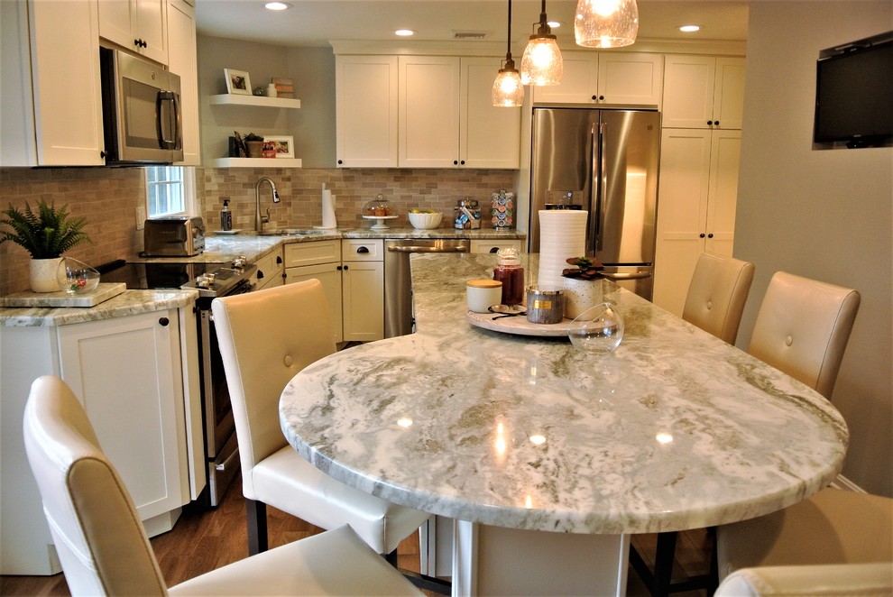 Inspiration for a transitional l-shaped medium tone wood floor kitchen remodel in Boston with an undermount sink, shaker cabinets, white cabinets, granite countertops, beige backsplash, subway tile backsplash, stainless steel appliances and an island
