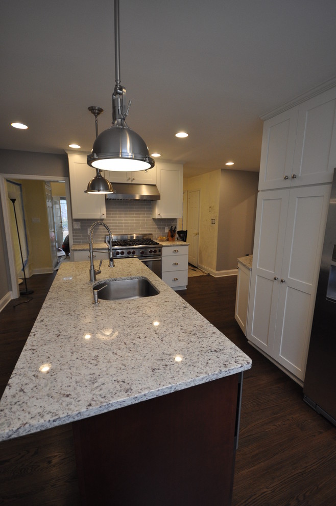 Example of a large transitional u-shaped dark wood floor and brown floor eat-in kitchen design in DC Metro with an undermount sink, shaker cabinets, white cabinets, green backsplash, subway tile backsplash, stainless steel appliances and an island