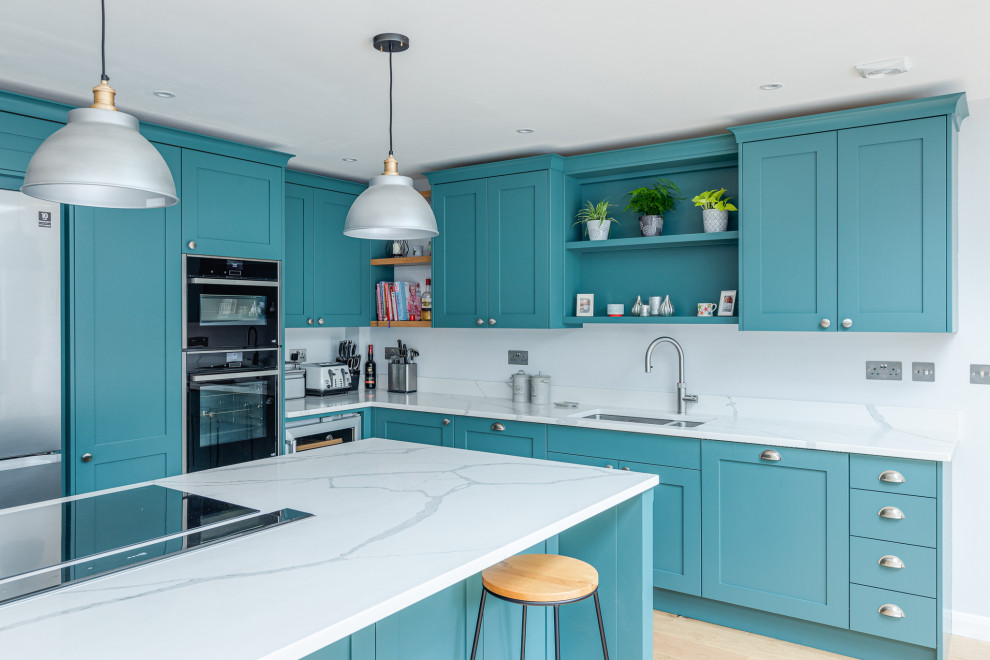 Design ideas for a large traditional l-shaped open plan kitchen in Hertfordshire with a drop-in sink, shaker cabinets, green cabinets, quartzite benchtops, panelled appliances, laminate floors, with island and white benchtop.