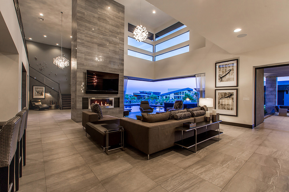 Photo of an expansive contemporary open concept living room in Las Vegas with beige walls, a ribbon fireplace, a wall-mounted tv, porcelain floors, a tile fireplace surround and brown floor.