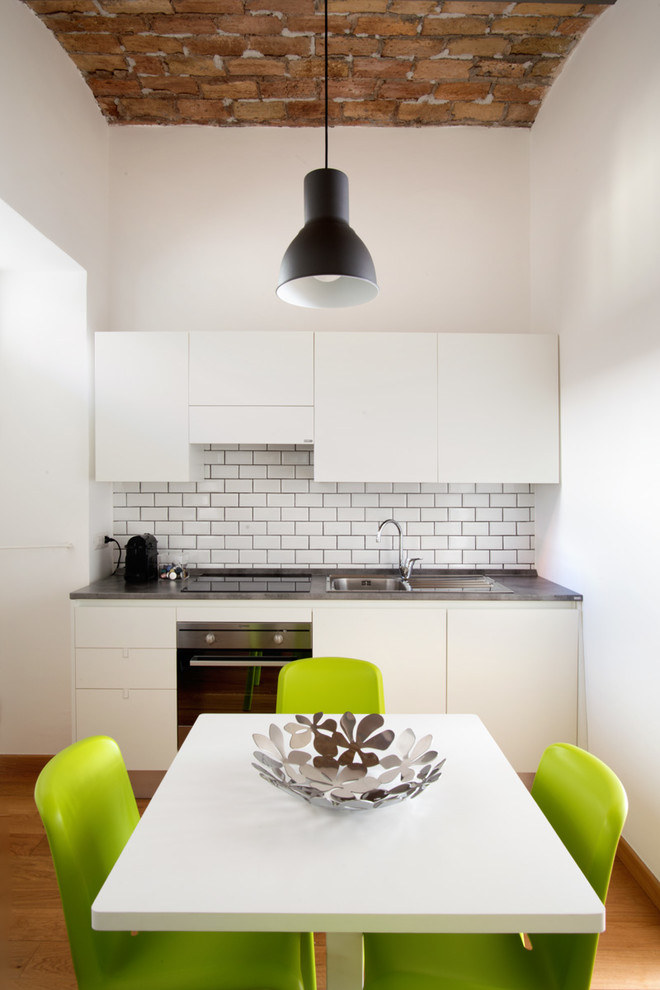 Design ideas for a small contemporary single-wall eat-in kitchen in Rome with no island, flat-panel cabinets, white cabinets, white splashback, subway tile splashback, medium hardwood floors and brown floor.