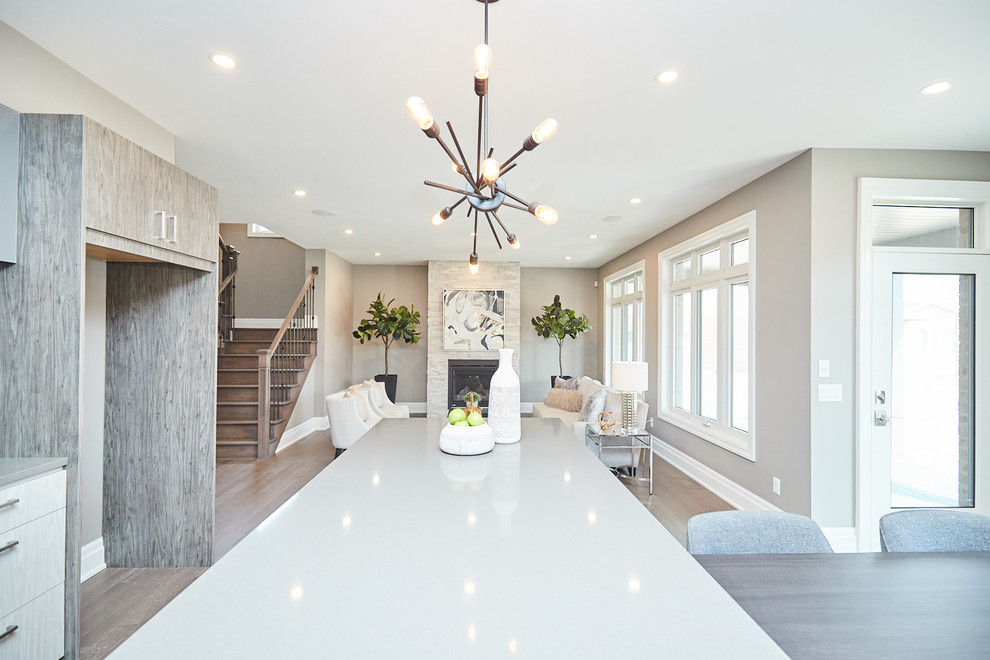 Example of a large transitional l-shaped medium tone wood floor and gray floor eat-in kitchen design with an undermount sink, flat-panel cabinets, gray cabinets, quartzite countertops, gray backsplash, stainless steel appliances, an island and gray countertops