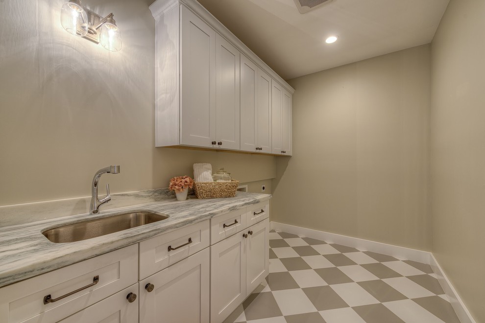 This is an example of a mid-sized traditional galley utility room in Phoenix with an undermount sink, recessed-panel cabinets, light wood cabinets, marble benchtops, green walls, marble floors and a side-by-side washer and dryer.