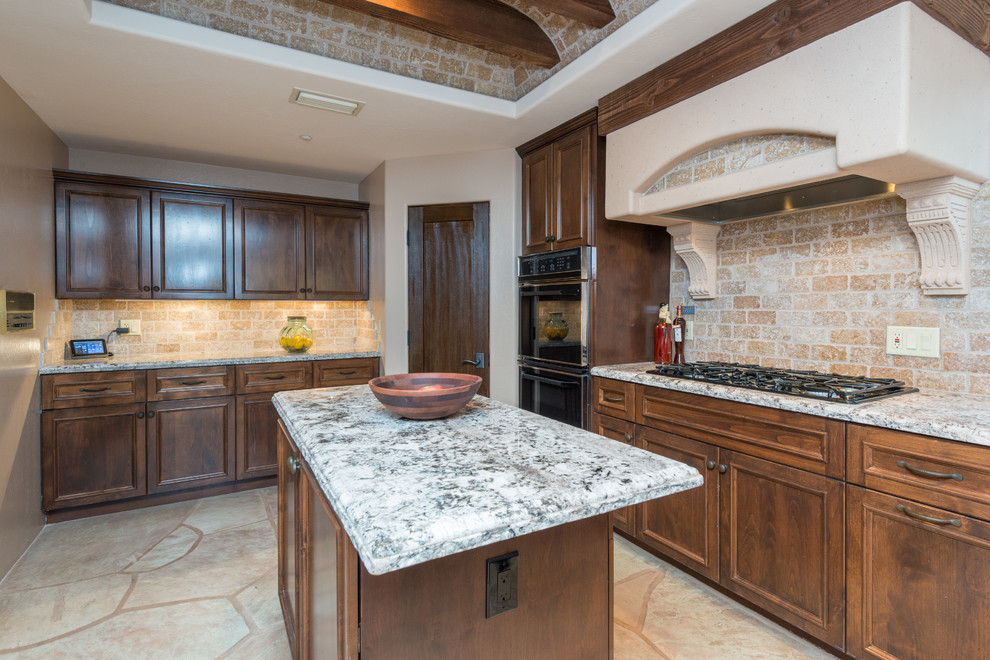 Inspiration for a large rustic slate floor eat-in kitchen remodel in Phoenix with a farmhouse sink, raised-panel cabinets, dark wood cabinets, granite countertops, beige backsplash, stone tile backsplash, paneled appliances and an island