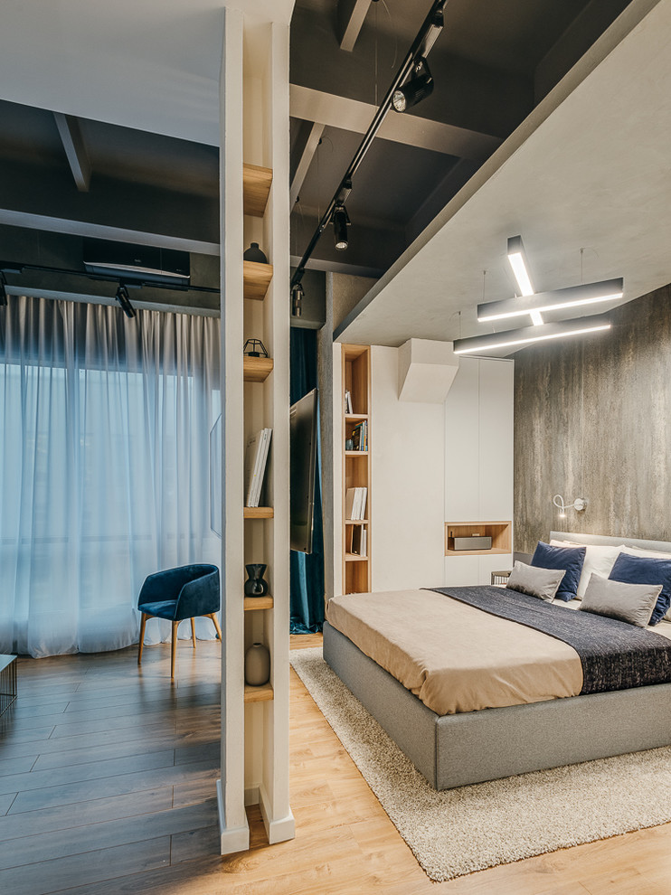 Photo of an industrial master bedroom in Moscow with grey walls, medium hardwood floors and brown floor.