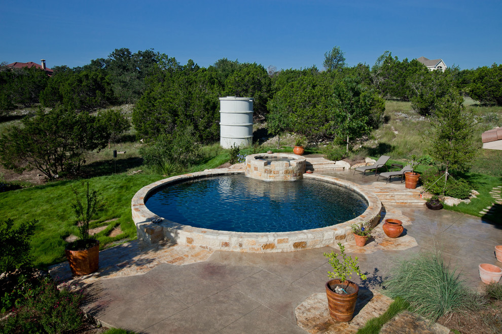 Design ideas for a mid-sized country backyard round aboveground pool in Austin with a water feature and stamped concrete.
