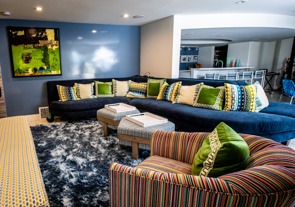 Modelo de sala de estar con barra de bar abierta actual grande con paredes azules y televisor colgado en la pared