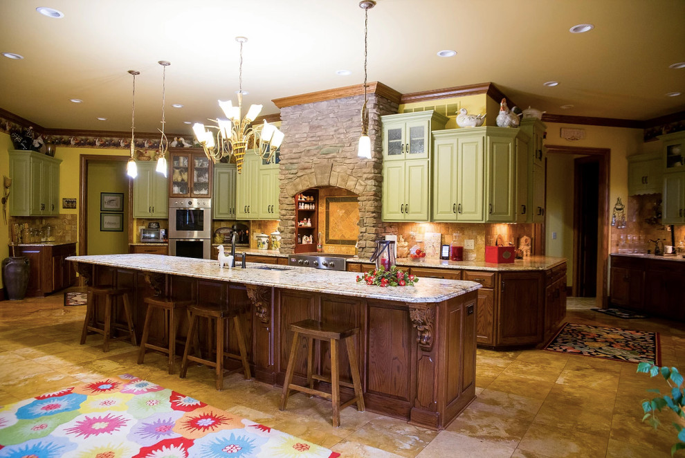 Example of a large mountain style u-shaped porcelain tile and beige floor eat-in kitchen design with an undermount sink, raised-panel cabinets, green cabinets, granite countertops, beige backsplash, porcelain backsplash, stainless steel appliances, an island and multicolored countertops