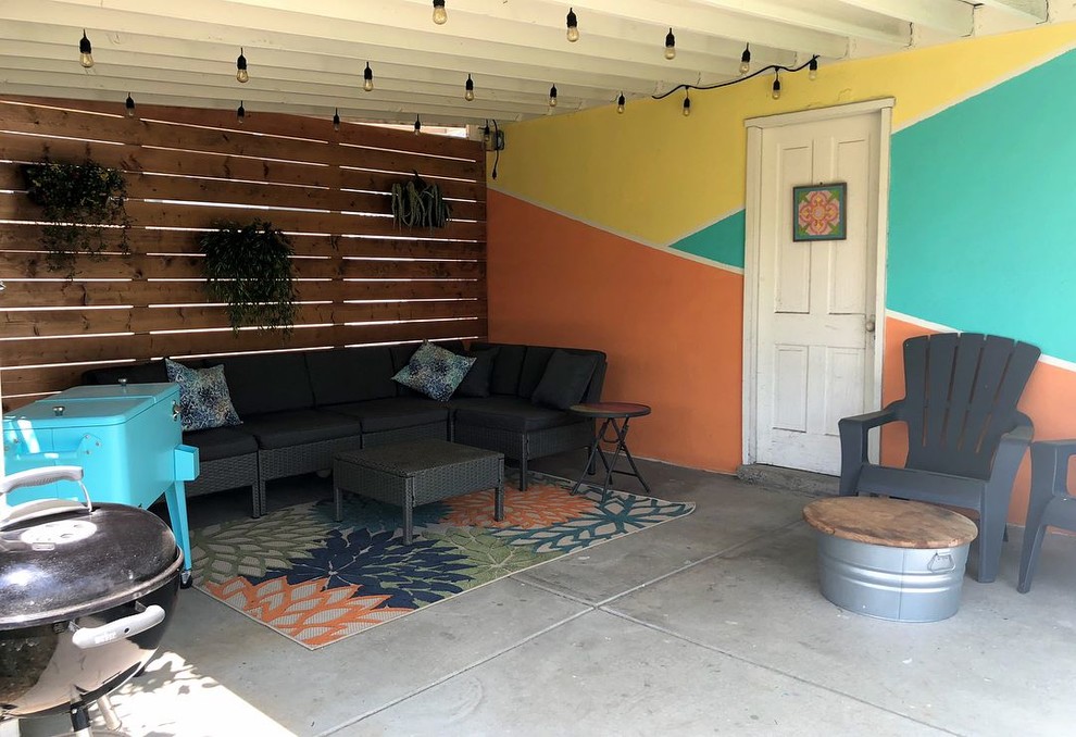 Small midcentury backyard patio in Orange County with concrete slab and a roof extension.